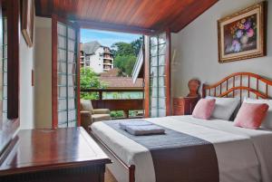 une chambre avec un lit et une grande fenêtre dans l'établissement Capivari - Lareira - Estilo Clássico de Casa de Campo, à Campos do Jordão