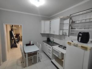 フロリアノポリスにあるApto studio no Centro de Floripa 201の白いキャビネット、白いテーブルと椅子付きのキッチン +6枚の写真