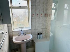 a bathroom with a sink and a shower with a window at Professional 4BR House - Lace Market, Uni, QMC, City Centre & M1 - Sleeps 8 in Nottingham