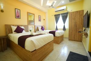 Un dormitorio con dos camas y un televisor. en M M Hotel Royal Respite, en Coimbatore