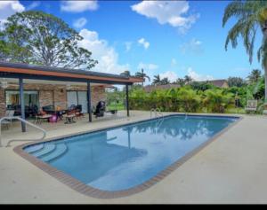 a swimming pool in front of a house at lone pine estate in Delray Beach