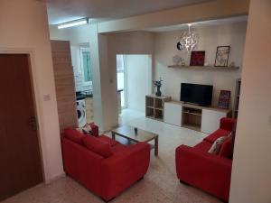 a living room with two red couches and a tv at Sea Breeze Maisonette in Larnaka