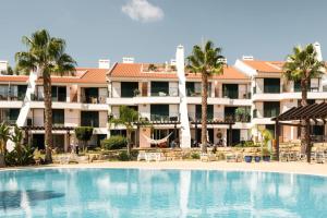 a swimming pool in front of a hotel at Birdsong Vila Sol Village by Experience MamiMi in Vilamoura