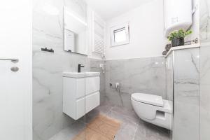 a white bathroom with a toilet and a sink at Apartman Simic in Trogir