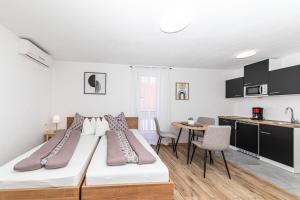 a bedroom with two beds and a kitchen with a table at Apartman Simic in Trogir