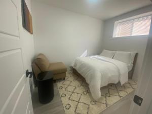 a bedroom with a bed and a chair and a window at Carrington Cozy Suite, Calgary in YYC