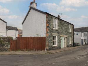 an old brick house with a wooden fence on a street at Capella Cottage in Keswick