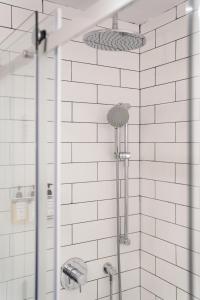 a shower in a bathroom with white tiles at Maison Saint-Vincent By Maisons & co in Montréal