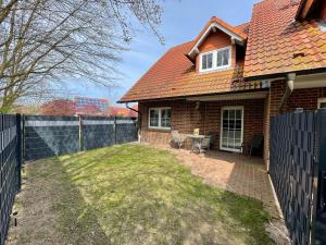 ein Haus mit einem Zaun und einem Tisch im Hof in der Unterkunft Haus Boddenruh Ferienwohnung Holz in Wiek auf Rügen 