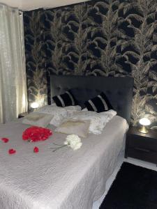 a bedroom with a bed with red and white flowers on it at BY NEPTUNE - Appartement Rustique JACUZZI in Bondy