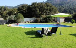 two chairs and an umbrella next to a swimming pool at A Broula Casa con piscina in Cangas de Morrazo