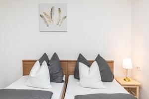 two beds with gray and white pillows in a room at Apartman Simic in Trogir