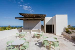 a patio with white tables and green chairs at Lalola DownTown Boutique Apartments in Puerto Morelos