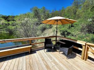 a deck with two chairs and an umbrella at Deer Haven Cabin in New Straitsville