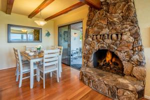 a living room with a stone fireplace and a table and chairs at Bluewater Retreat by Paradise Retreats in Santa Barbara +25 photos