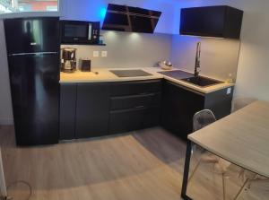 a kitchen with a black refrigerator and a table at L'Iliade 3 in Grenoble