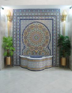 a bathroom with a large mosaic tile wall with a tub at Asswar Al Madina in Fès