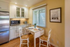 a kitchen with white cabinets and a table and chairs at Casa Azul by Paradise Retreats in Santa Barbara