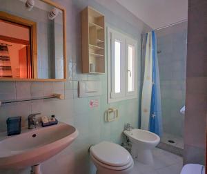 a white bathroom with a sink and a toilet at Onda Su Onda Appartamenti in Seccheto
