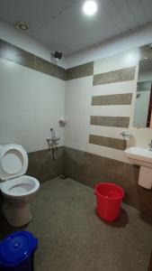 a bathroom with a toilet and a sink and a bucket at Birdwing Cottage, Munnar in Munnar