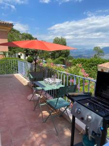 a patio with a table and a grill and an umbrella at Maison Barnoin-Chambres et villas au calme proche Nice in Bouyon