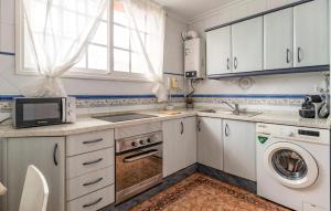 a kitchen with white cabinets and a washer and dryer at Stunning Home In Chiclana De La Fronter in Chiclana de la Frontera