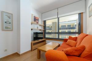 a living room with an orange couch and a large window at Playa Sanxenxo in Sanxenxo