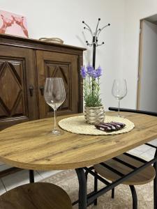 a wooden table with two wine glasses and purple flowers at La maison du 4 in Épernay