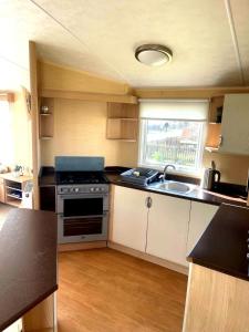 eine kleine Küche mit Herd und Spüle in der Unterkunft Spacious 8-Berth Caravan at Unity Beach Resort in Brean