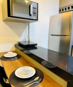 a kitchen with a table with two plates and a microwave at Studio Duo Jk Panorama 4 in Sao Jose do Rio Preto