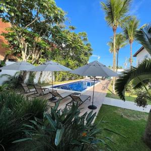 a swimming pool with umbrellas and chairs next to a resort at Makai Hotel Boutique - Frente Mar in Guarujá
