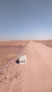 a bag laying on the side of a dirt road at ama in Ismant