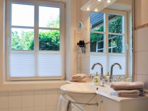 a bathroom with a sink and two windows at Haus am Deich in Utersum