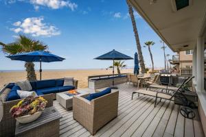 ニューポートビーチにあるLuxurious Oceanfront Home with Incredible Viewsのビーチに家具とパラソルが置かれたデッキ