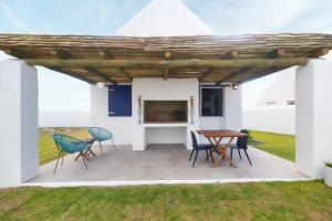 a patio with a table and chairs and a table and chairs at 4131 Beach Drive Bliss & Flip Flop Cottage in Struisbaai