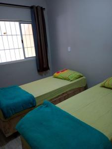 Dos camas individuales en una habitación con ventana. en Pousada Nilda Maria, en Cachoeira Paulista