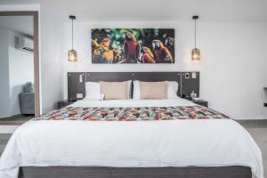 a bedroom with a large white bed with birds on the wall at Azor Hotel Cali Versalles in Cali