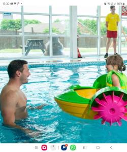 a man and a girl in a swimming pool with a toy boat at Daisy Lodge Lilac Grove 3 in Waxholme