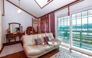 a living room with a couch and large windows at Spa Pension Basso in Sokcho