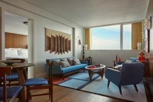 - un salon avec un canapé bleu et un lit dans l'établissement Sea Containers London, à Londres