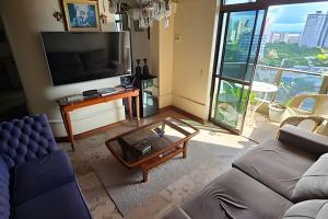 a living room with a couch and a tv at Ed. Delta Gardenn in Carmo