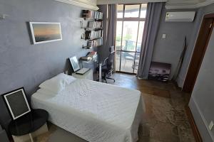 a bedroom with a bed and a desk with a computer at Ed. Delta Gardenn in Carmo
