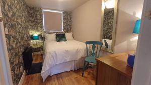 a small bedroom with a bed and a chair at Garden Apartment Morpeth- with lockable bike storage! in Morpeth