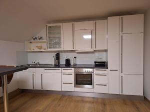 a white kitchen with white cabinets and a stove at Ferienwohnung Varbrook in Niederkrüchten