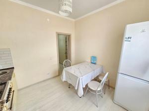 a kitchen with a table and a white refrigerator at Mars APARTMENTS KZ 4Б in Aktobe