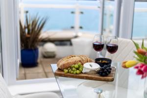 a plate of food and two glasses of wine on a table at NEW! Stunning 2 Bed Beach Front Penthouse Apartment - Topaz, Compass Point in Carbis Bay