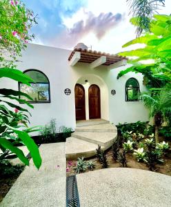 a white house with a brown door and some plants at King Bed, Kitchen, Saltwater Pool, Fast Wifi, Air Conditioning - Flor at Casa Calavera in San Francisco