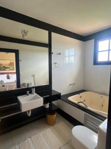 ein Badezimmer mit Badewanne, Waschbecken und Spiegel in der Unterkunft Fazenda do Barro CMD Maravilhosa Casa de Fazenda in Conceição do Mato Dentro