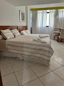 a large bed in a bedroom with a tiled floor at Flat Privativo Sol Victoria Marina in Salvador