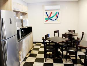 a kitchen with a table and chairs and a refrigerator at IT'S Suítes in Artur Nogueira